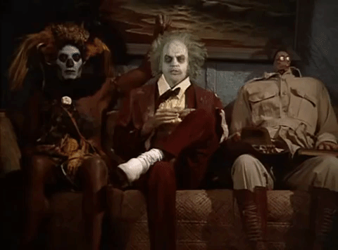 cena do filme Os Fantasmas se Divertem em que 3 fantasmas esquisitos estão sentados no sofá de uma sala de espera enquanto a cabeça de um deles se encolhe