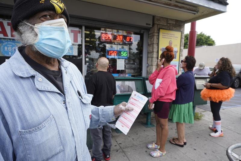 Philip Smith, wears a face mask and gloves as he lines up to purchase his lottery tickets for the Powerball lottery at the Blue Bird Liquor store in Hawthorne, Calif., Monday, Oct. 31, 2022. The jackpot for Monday night's drawing soared after no one matched all six numbers in Saturday night's drawing. It's the fifth-largest lottery jackpot in U.S. history. (AP Photo/Damian Dovarganes)