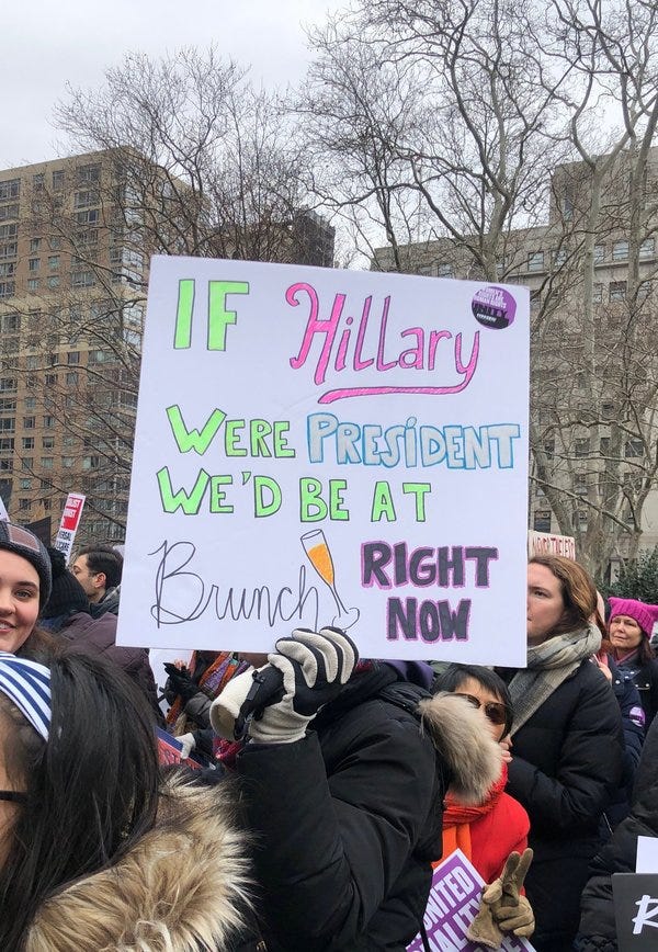 In a protest, a person holds a handmade sign, which reads "If Hilary were president we'd be at brunch right now."