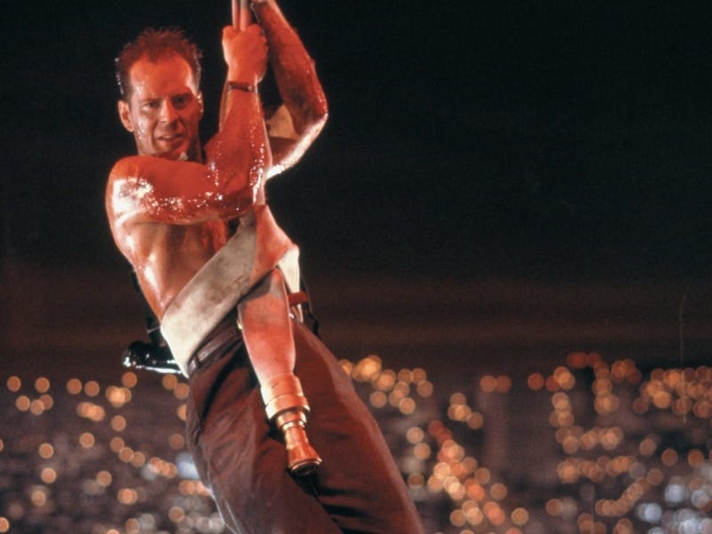 McClane hanging off the side of the building using a firehose wrapped around his body, blood dripping down his face.