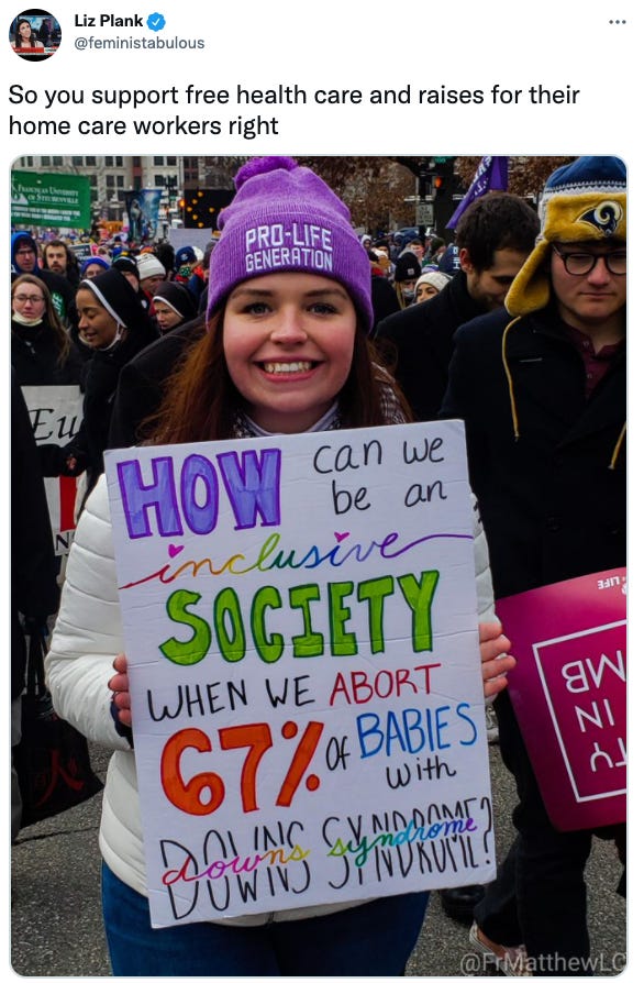 woman holds sign that says 67% of people with down syndrome are aborted