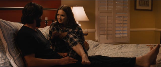 Winona Ryder in pyjamas in bed with her leg over Keanu Reeves