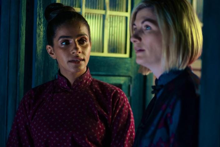 This image shows Yasmin "Yaz" Khan (played by Mandip Gill) on the left and the Thirteenth Doctor (played by Jodie Whittaker) on the right. They stand in the TARDIS's open front door wearing costumes appropriate for 19th-Century China. Yaz looks affectionately at the Doctor, who stares straight ahead. This image shows Yasmin "Yaz" Khan (played by Mandip Gill) on the left and the Thirteenth Doctor (played by Jodie Whittaker) on the right. They stand in the TARDIS's open front door wearing costumes appropriate for 19th-Century China. Yaz looks affectionately at the Doctor, who stares straight ahead.