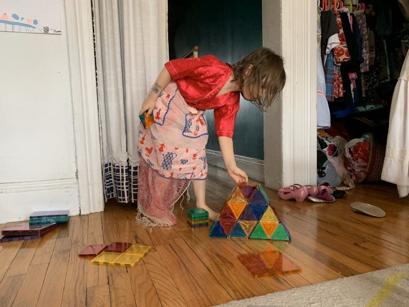 a girl building a pyramid from magnatile blocks