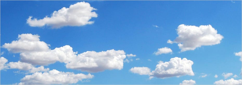 A photo of puffy white clouds against a bright blue sky.
