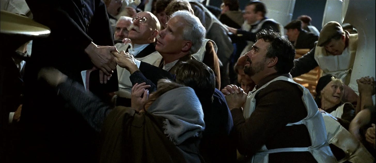 In a scene from the 1997 film 'Titanic', terrified passengers kneel on the deck praying with a Catholic priest and clutching his hand, which holds a Bible