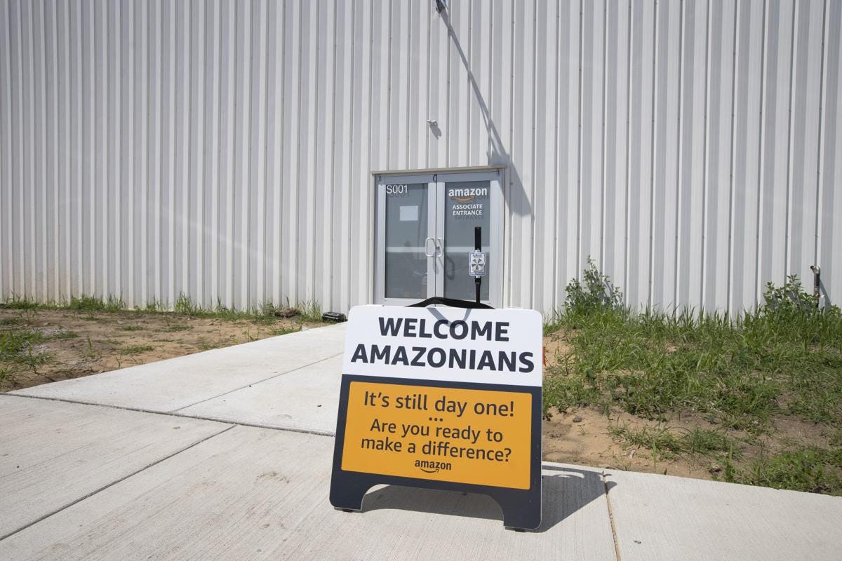 A sign reads "Welcome Amazonians" outside a new warehouse