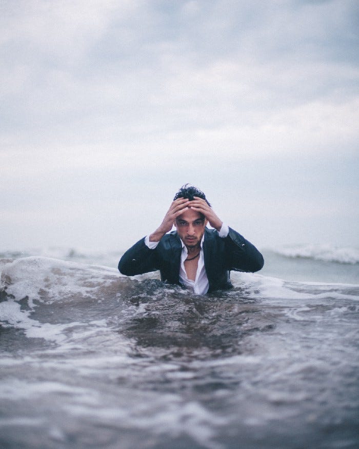 Man in a business suit getting out of water