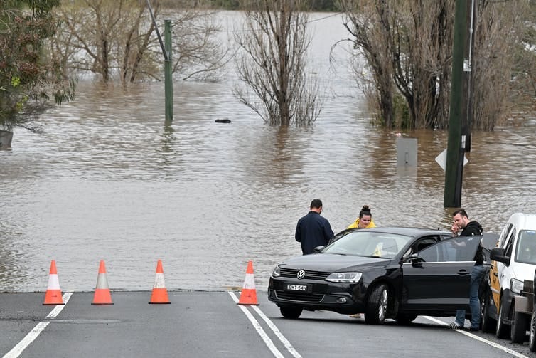 flooded road with cars parked and people standing