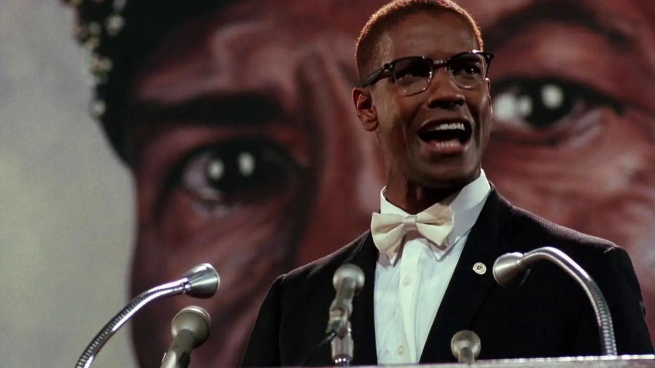This image shows Malcolm X (played by Denzel Washington) speaking at a Nation of Islam rally in Spike Lee's 1992 movie Malcolm X. Malcolm, wearing a bowtie, stands in front of a large portrait of Elijah Muhammad (painted in the likeness of Al Freeman Jr., who plays Elijah in Lee's film). This image shows Malcolm X (played by Denzel Washington) speaking at a Nation of Islam rally in Spike Lee's 1992 movie Malcolm X. Malcolm, wearing a bowtie, stands in front of a large portrait of Elijah Muhammad (painted in the likeness of Al Freeman Jr., who plays Elijah in Lee's film).