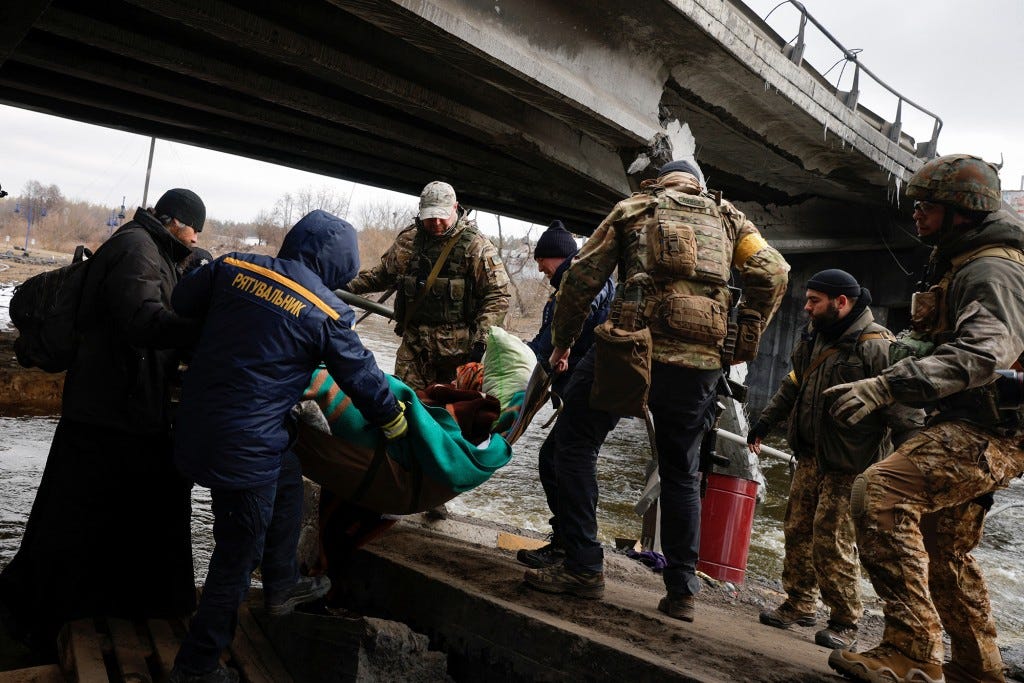 Ukrainian servicemen evacuate a person across Irpin River below a destroyed bridge as Russia's attack on Ukraine continues in Irpin outside Kyiv, Ukraine, March 9, 2022.