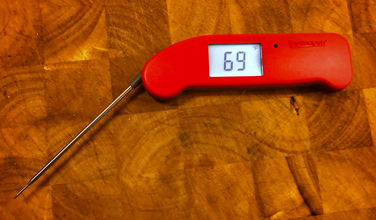 Open digital thermometer on a cutting board. The display reads 69 degrees Fahrenheit.