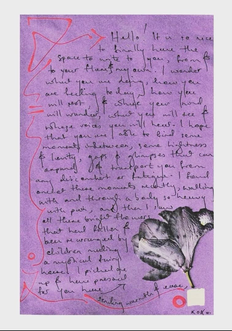 A purple page against a pale blue background featuring a handwritten note in black ink with pink decorations around the edge. There is a pressed flower on the page.
