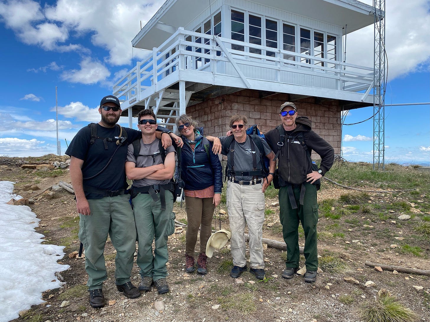 A group of people posing together outside of a white mountaintop tower.