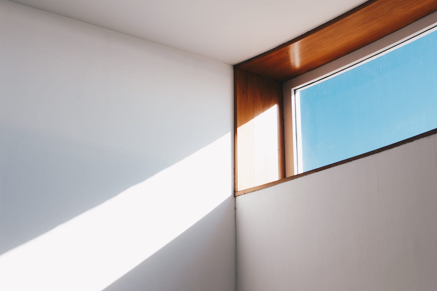 a light shining through a window at the corner of the wall and ceiling