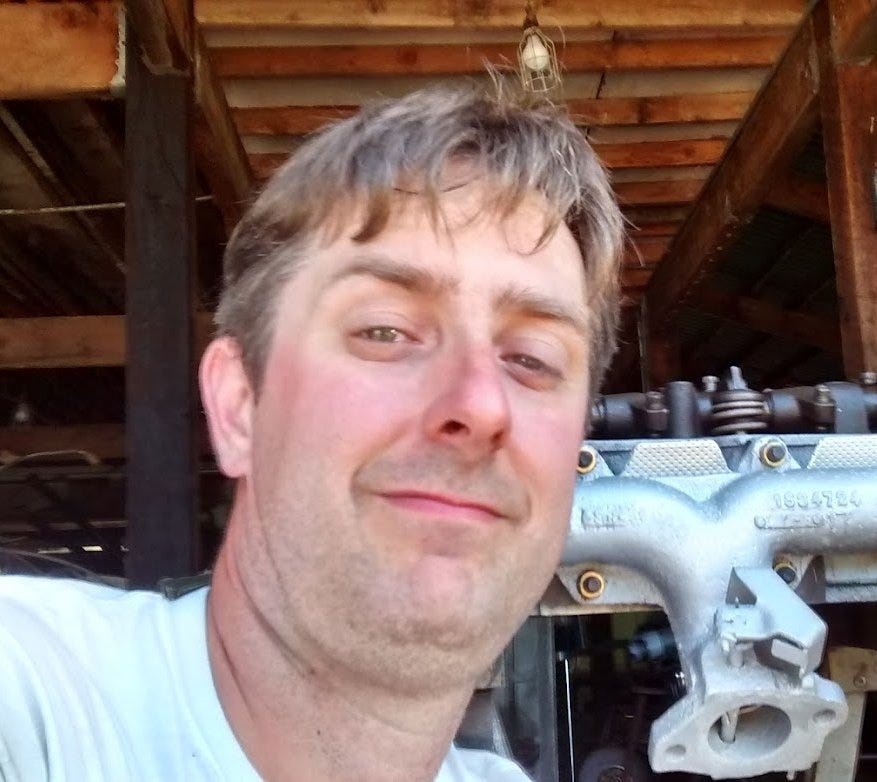 Mass shooter Benjamin Jeffrey Smith posing with his thumbs up in front of Machines. Wearing a white T-shirt