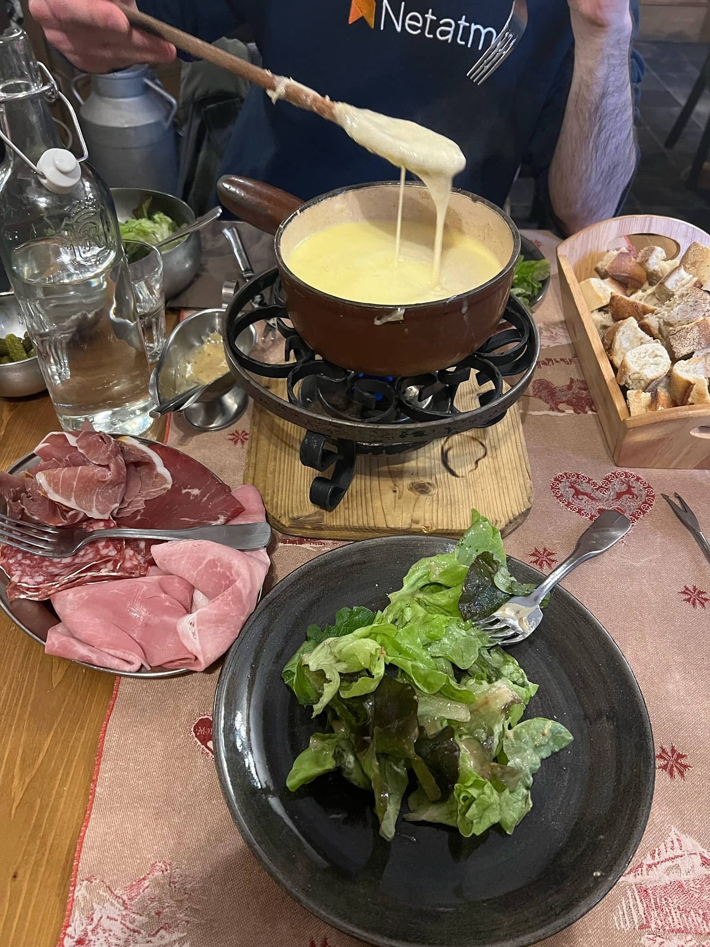 Cheesy fondue with some bread, meat, and salad.