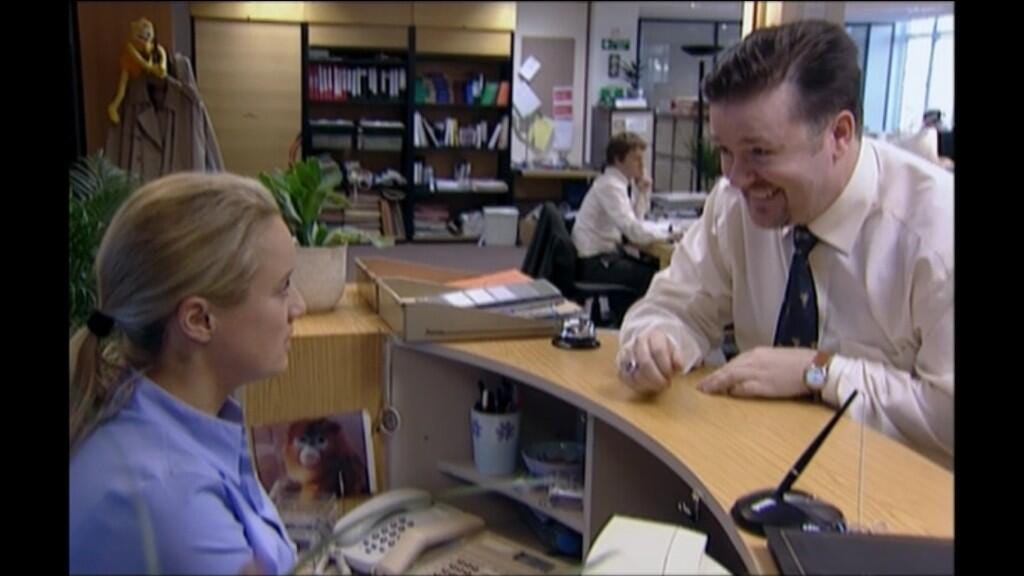 David Brent from The Office with a big grin on his face as Dawn looks at him incredulously.