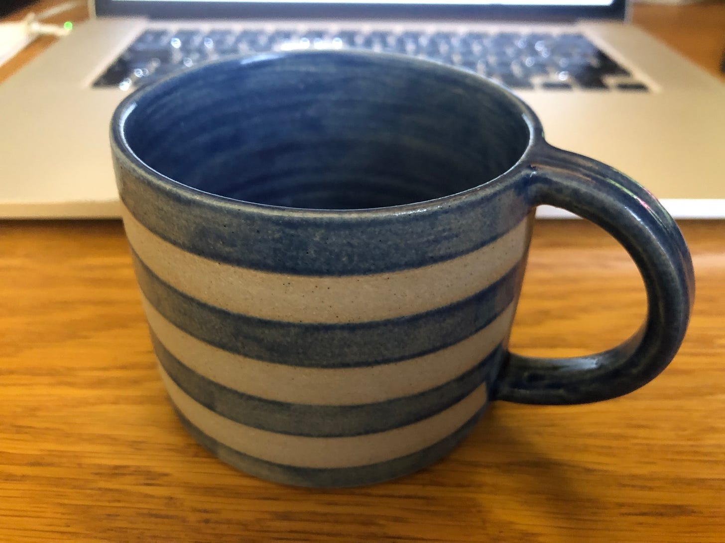 Ceramic mug with fawn (bare clay) and blue (light glaze) hoops. Blue handle of the perfect size – none of your fiddly nonsense.