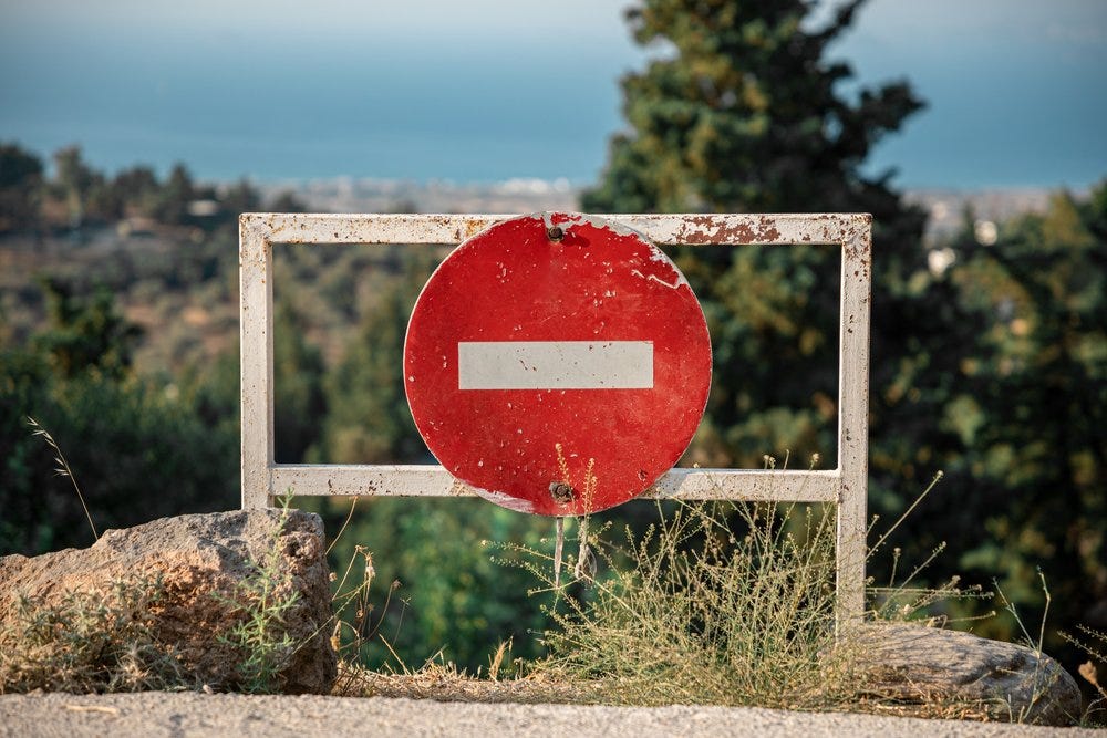 A circular stop sign in red and white attached to a white metal frame