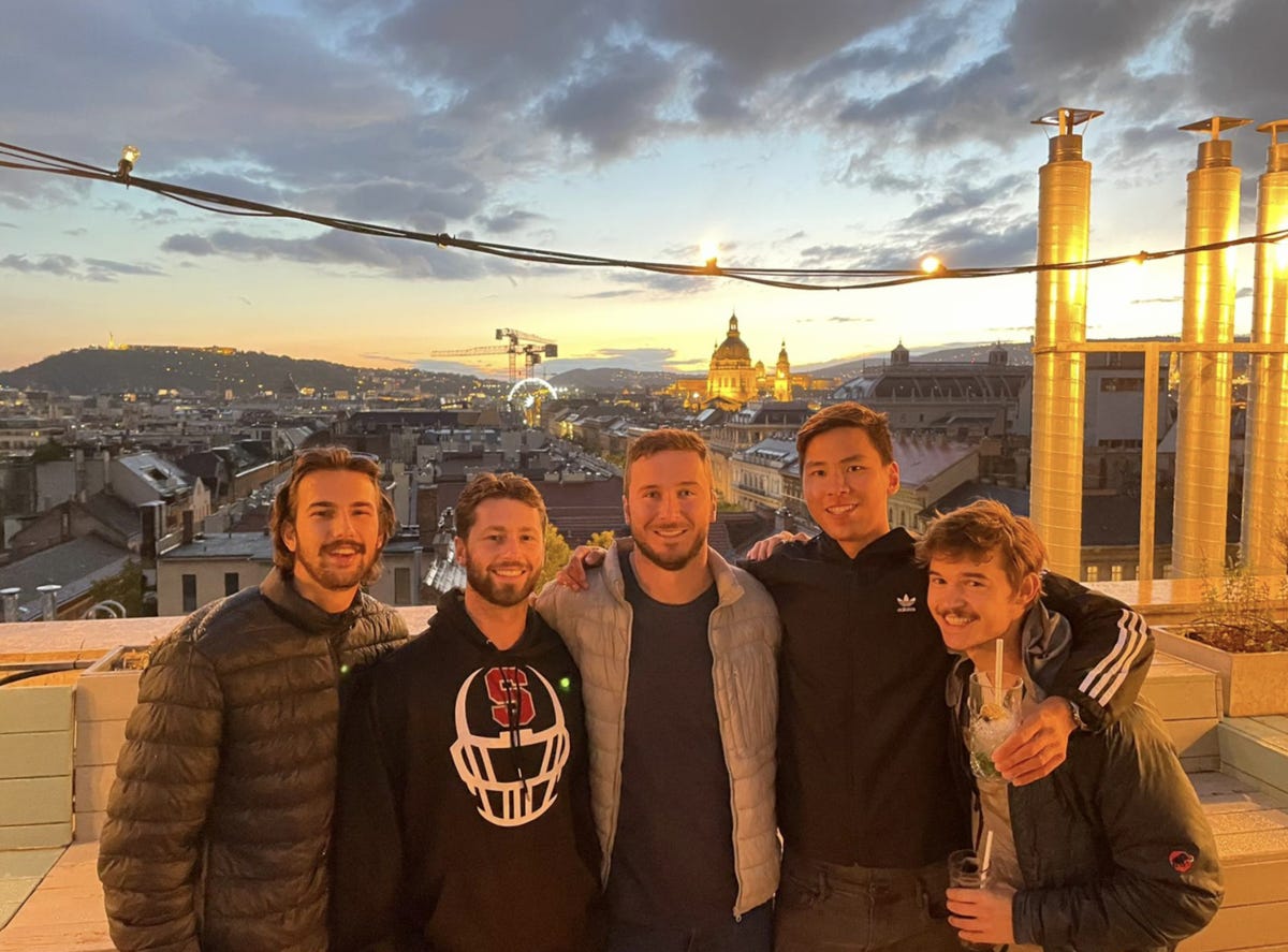 A group of people posing for a photo in front of a city

Description automatically generated