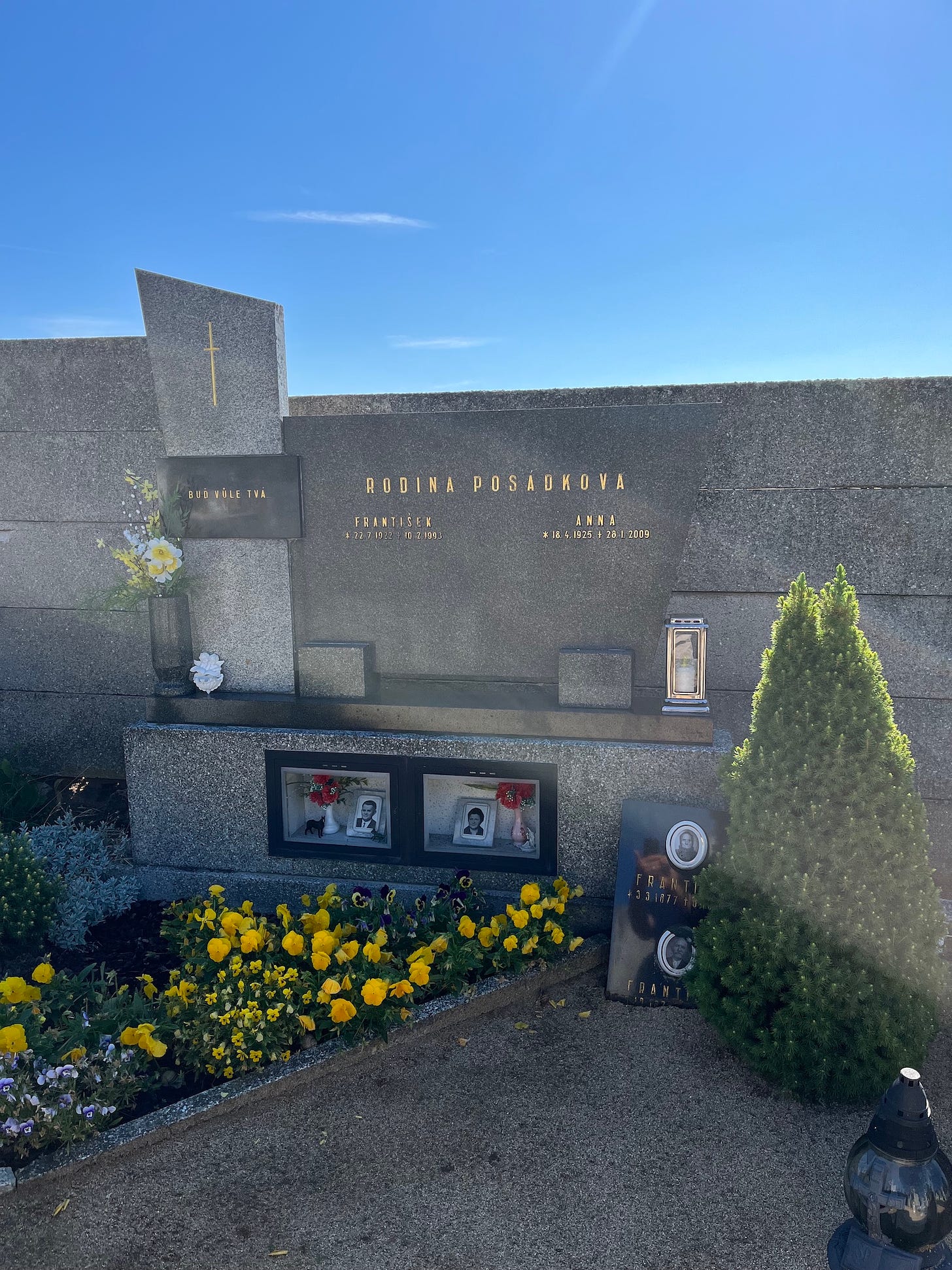 Family grave plot in Czechia, blue sky, flowers and family photos at the grave