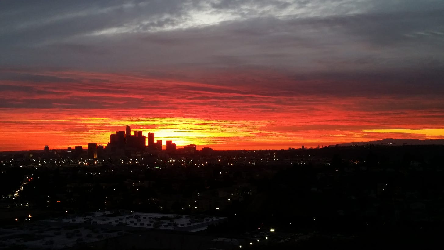 Image of downtown in a bright orange/red sunset.