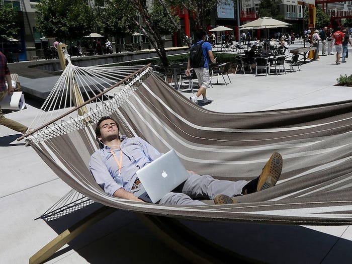 Man lying in a hammock with eyes closed and a Macbook on his lap