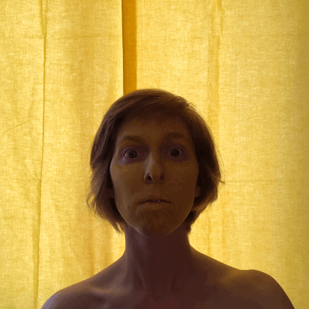 Rainbow Squared Year 5, Piece Nineteen: 17. Yellow Yellow. Animated loop of a yellow background lit from behind with ilyse in silhouette, then face moving forward to overexpose background and reveal ilyse’s face painted yellow.  