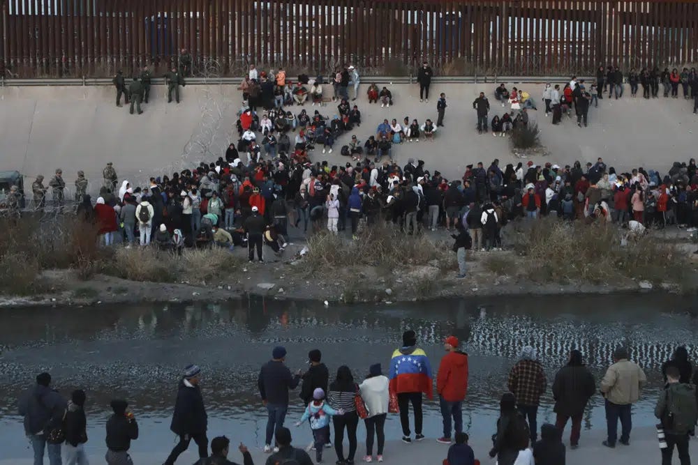 Migrants gather at a crossing into El Paso, Texas, as seen from Ciudad Juarez, Mexico, Tuesday, Dec. 20, 2022. Tensions remained high at the U.S-Mexico border Tuesday amid uncertainty over the future of restrictions on asylum-seekers, with the Biden administration asking the Supreme Court not to lift the limits before Christmas. (AP Photo/Christian Chavez)