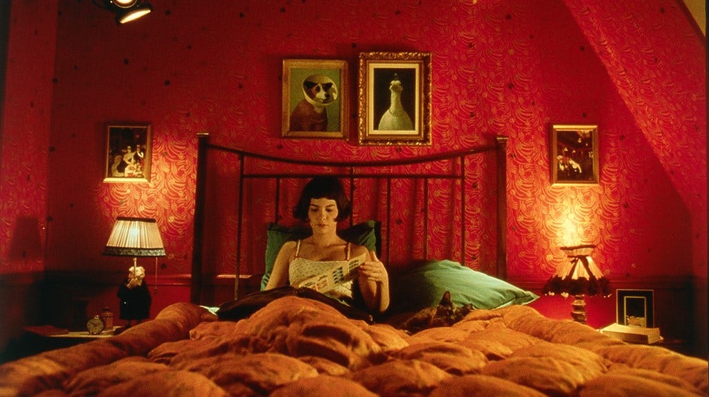 A woman sits in bed, flipping through a photo album. Her room is basked in warm, red light, and there is a cat in bed with her.