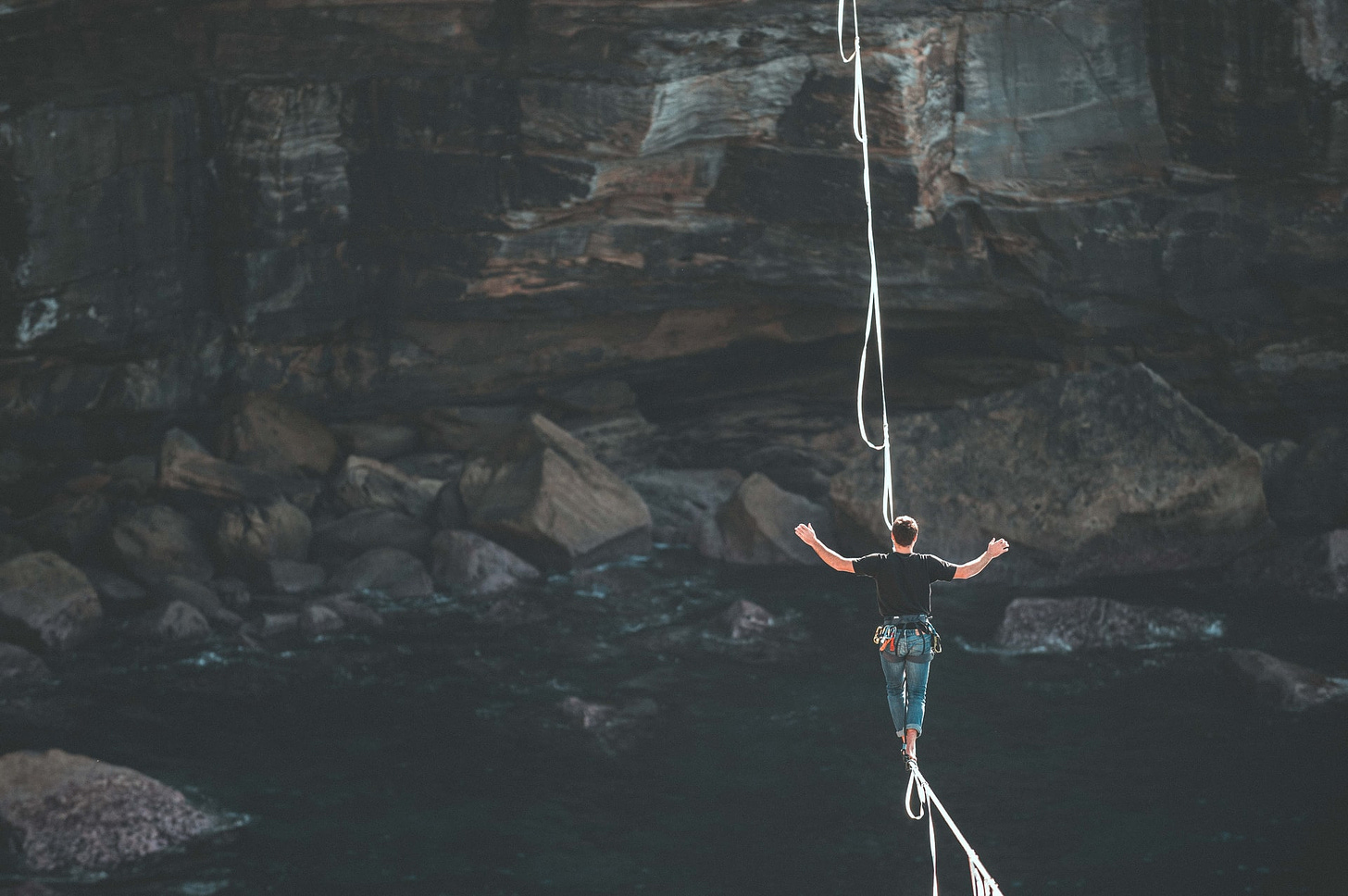 a person with short hair walking on a rope over a river. Photo by Loic Leray on Unsplash