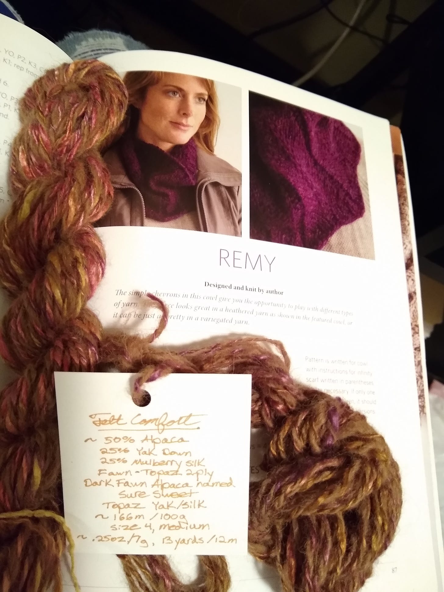 Two mini-skeins on an open knitting book, and one handwritten yarn label.