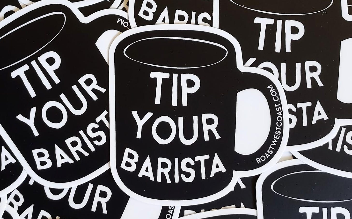 Close up of a white and black sticker. White background. A black camp-style coffee mug with some handdrawn block letters that say Tip Your Barista adorn the side.