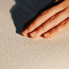 Mão de uma mulher lendo um livro em Braille