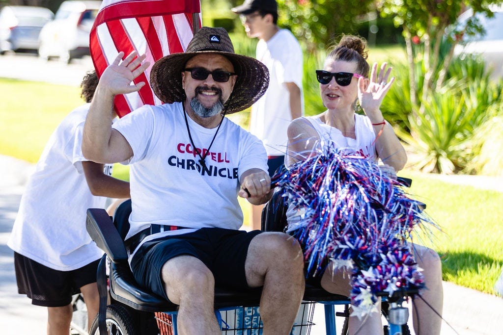 Husband and wife on a two-person tricycle in a parade