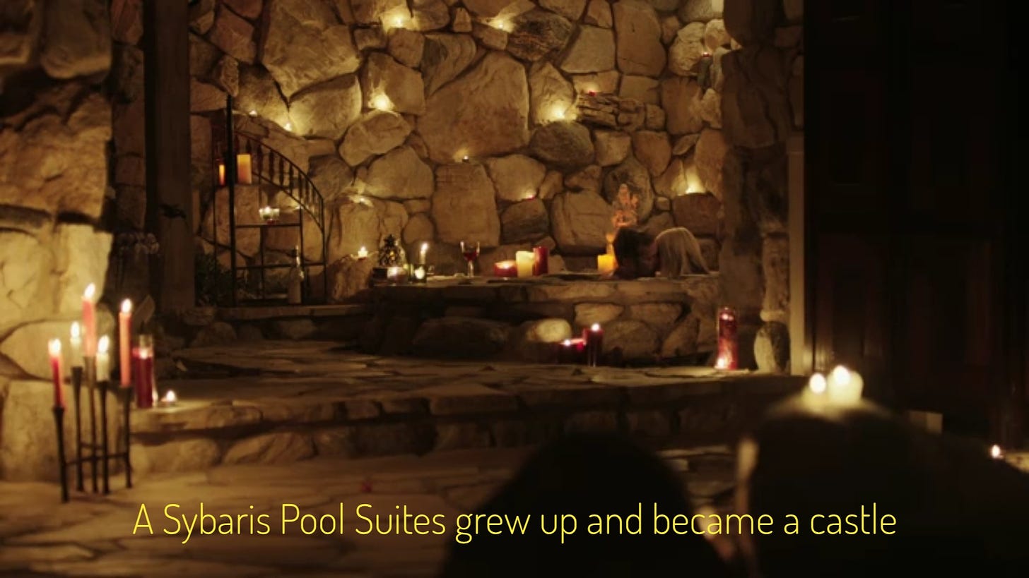 ID: a stone room with lots of candles and a stone hot tub, with two white people smooching in it. Captioned "A Sybaris Pool Suites grew up and became a castle."