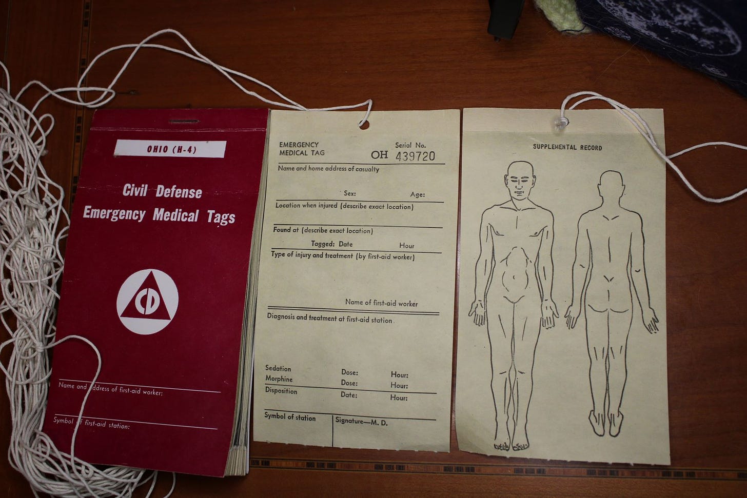 Civil Defense Medical Tags booklet, with both sides of a tag displayed next to it, This emergency tag allows first aid workers to tag bodies after a nuclear blast, identifying treatable and untreatable injuries.