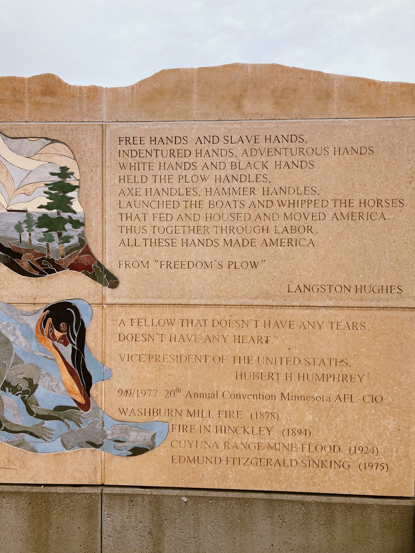 a beige monument with an exerpt of langston hughes' freedom's plow poem and a quote from hubert humphrey also shows a bit of an impressionist mural