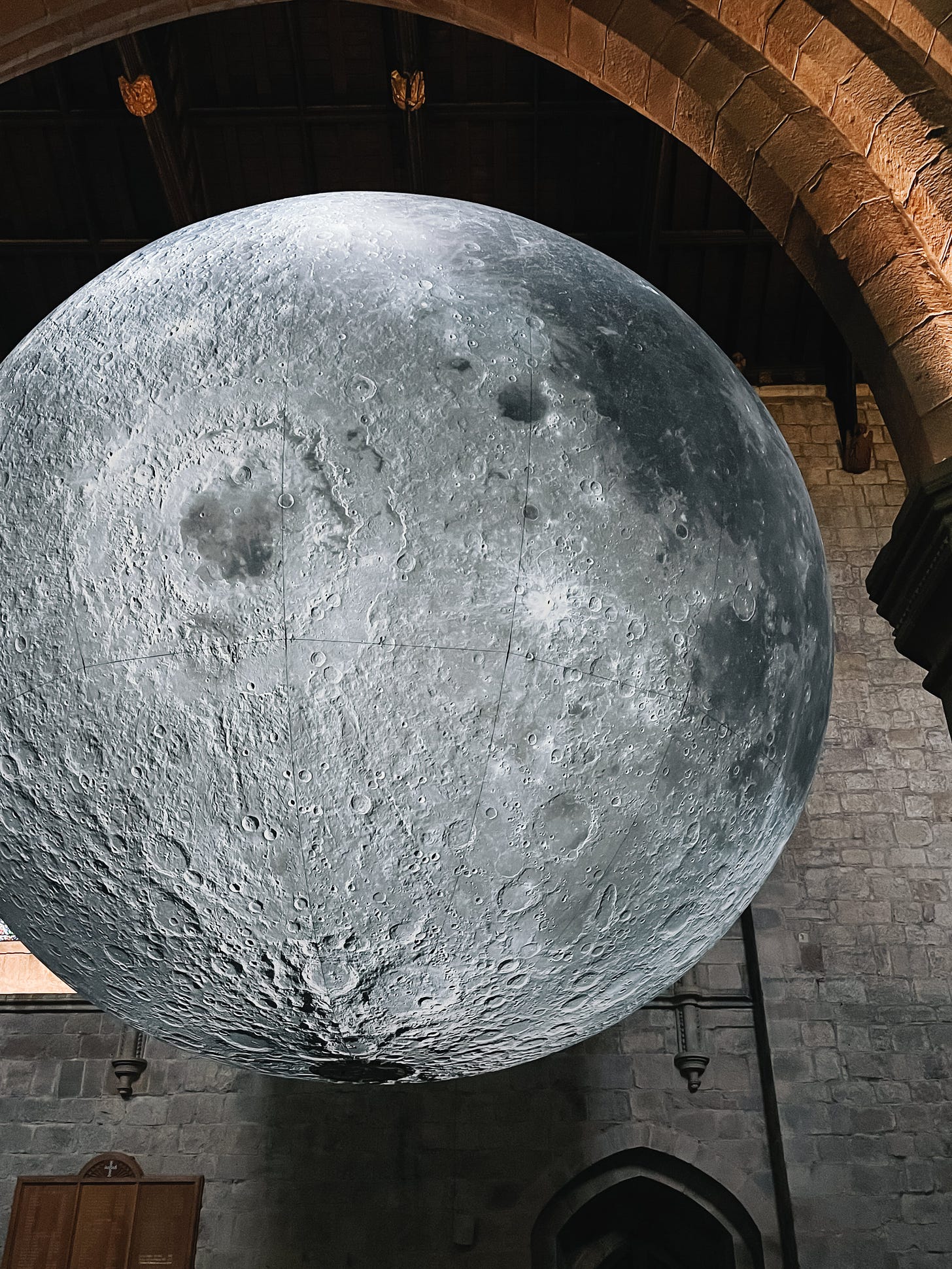 The stone archway of a church with a huge blowup ballon. Projected onto the balloon are images of the moon's craters.