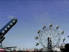 Gif of a man being shot out of a cannon in front of a ferris wheel