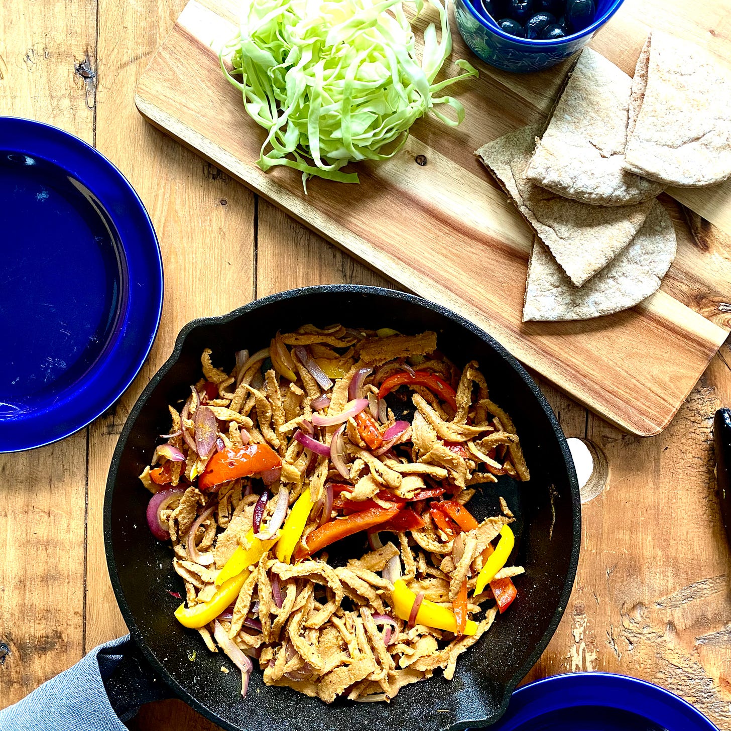 Skillet with plant-based kebab, peppers, onions, served with pitta bread and shredded cabbage