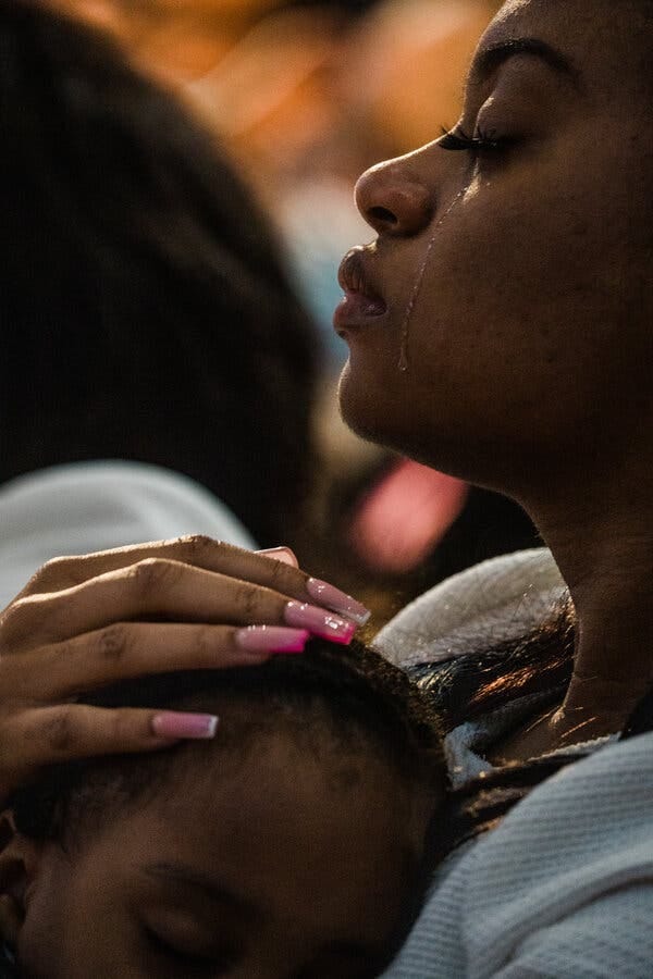 Charon Reed weeps at her grandmother’s funeral as her son Koda Anderson naps.