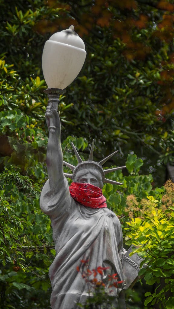 Lady Liberty wears a COVID mask