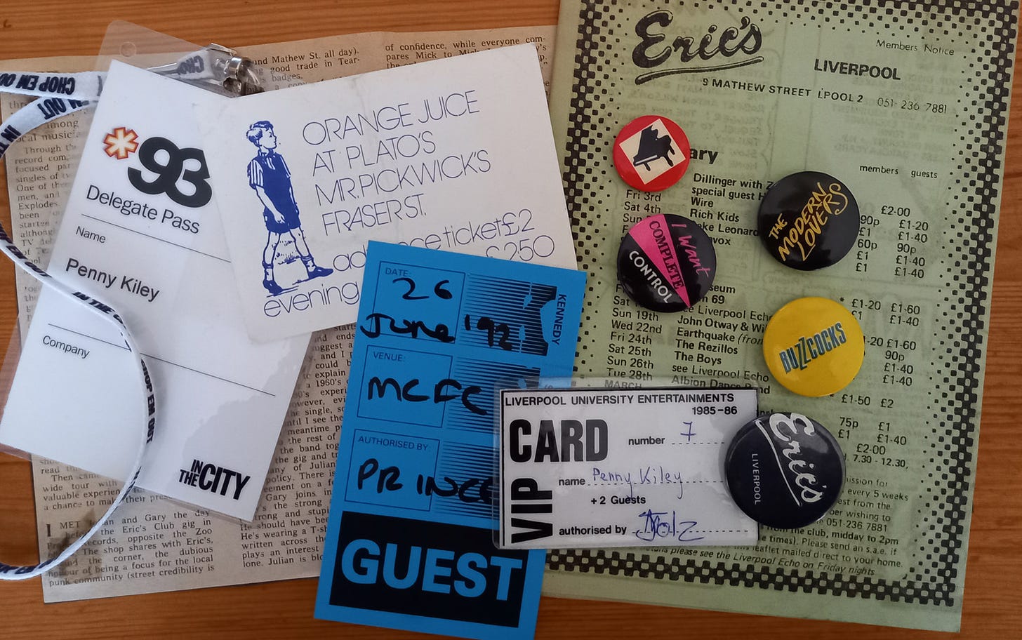 A random selection of music memorabilia: a press cutting, a flyer from Eric's club, some tickets and guest passes, and a sprinkling of punk-era badges.