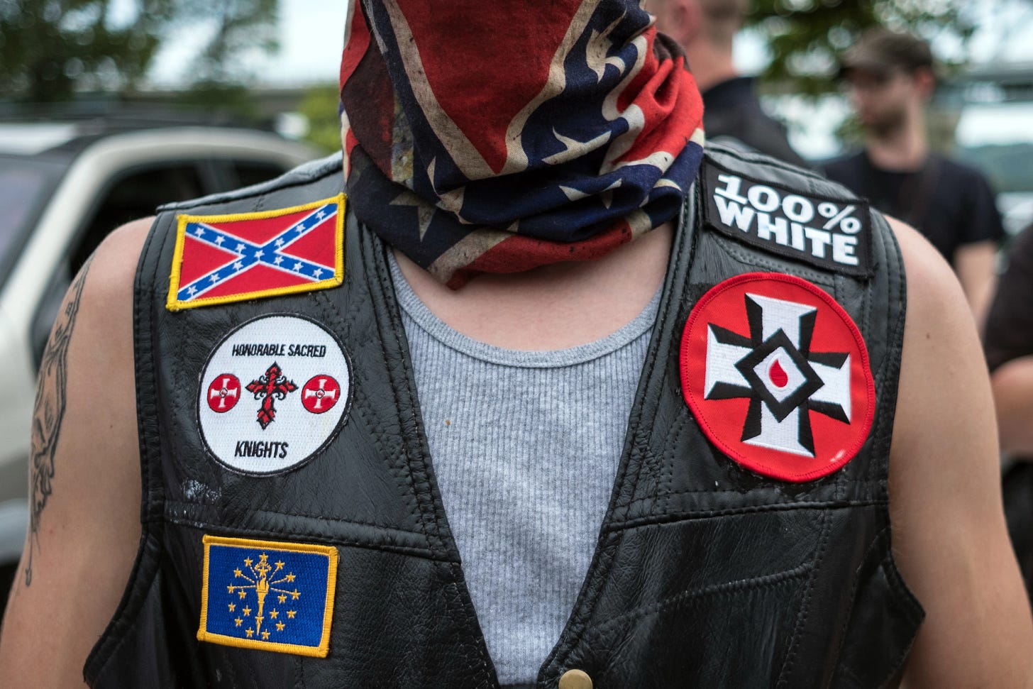 Photo: White man in black leather vest with white supremacist patches sewn on