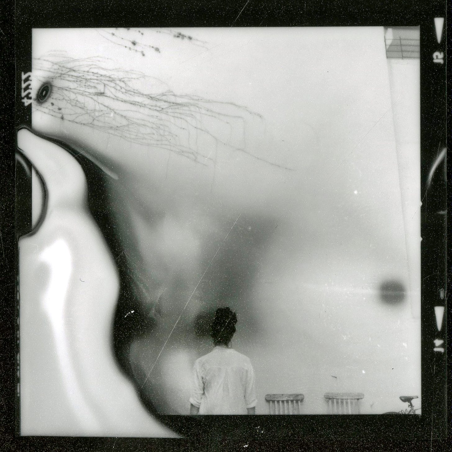 an emulsion test photo with a central figure, back facing the viewer, in black and white