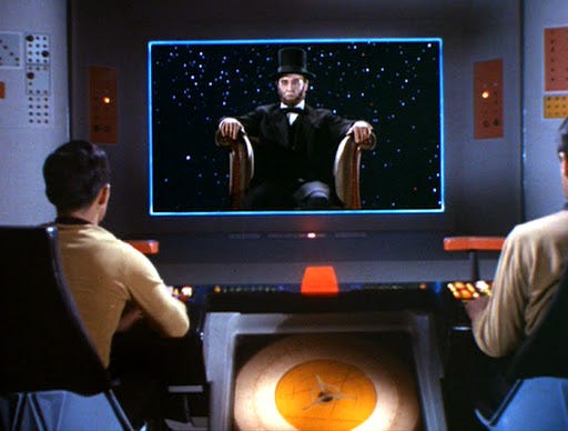 This image shows the bridge viewscreen of the U.S.S. Enterprise (NCC-1701) in the Star Trek Original Series Season 3 episode "The Savage Curtain." An image of Abraham Lincoln (played by Lee Bergere) sits in a chair and floats in space, amid a starfield, on the viewscreen. Hikaru Sulu (played by George Takei) sits at the Enterprise's helm (on the left) and an unnamed crewman sits at the navigator's position (on the right). Both Sulu's and the navigator's backs are to camera. This image shows the bridge viewscreen of the U.S.S. Enterprise (NCC-1701) in the Star Trek Original Series Season 3 episode "The Savage Curtain." An image of Abraham Lincoln (played by Lee Bergere) sits in a chair and floats in space, amid a starfield, on the viewscreen. Hikaru Sulu (played by George Takei) sits at the Enterprise's helm (on the left) and an unnamed crewman sits at the navigator's position (on the right). Both Sulu's and the navigator's backs are to camera.