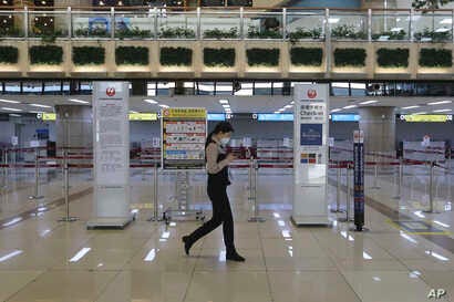 A Gimpo Airport official wearing a face mask passes by check-in counters of Japan Airlines at Gimpo Airport in Seoul, South…