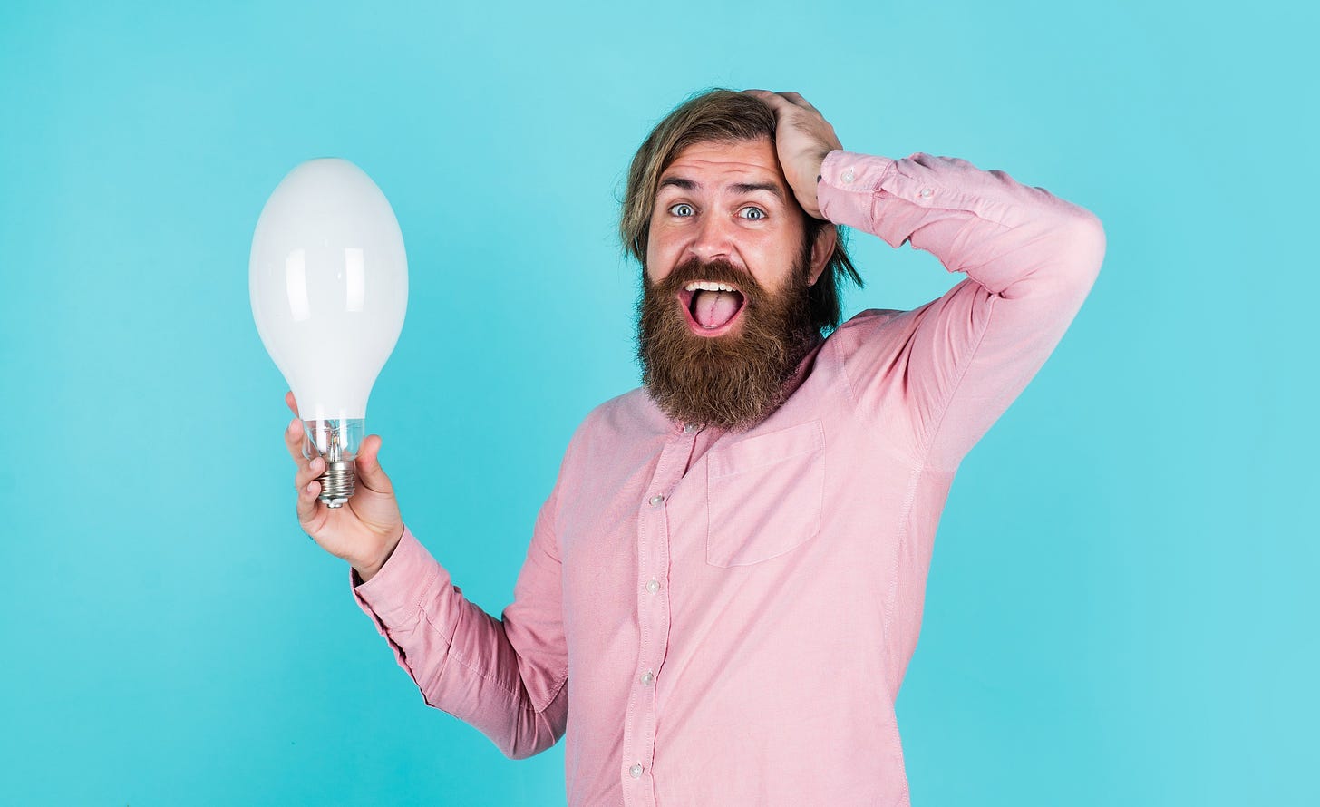 man with surprised expression holding a lightbulb